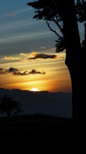 Captivating scene of the sun setting behind the silhouetted mountains, viewed from a vantage point