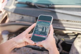 A person uses a smartphone to photograph car damage for insurance documentation The image