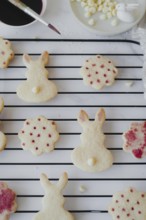 Top view of Easter bunny-shaped cookies delicately painted with hibiscus tea on a cooling rack. The
