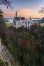 Neuschwanstein Castle stands majestically amidst a vibrant autumn forest in the Bavarian Alps
