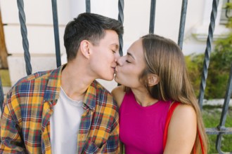 A happy lesbian couple shares a tender kiss while seated together, embracing love and affection.