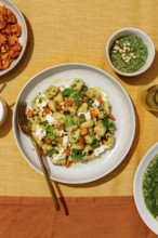 Top view of a colorful plate featuring potato gnocchi tossed with green pesto, garnished with