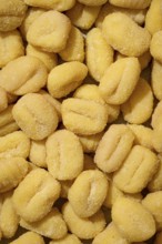 Top view of uncooked frozen gnocchi dusted with flour, closely packed and showing clear