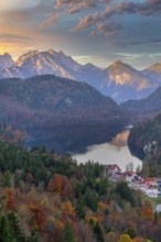 A picturesque view of a village nestled near a serene lake, surrounded by autumn foliage and the