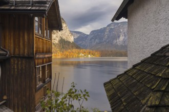 Scenic autumn view of Hallstatt Lake, framed by traditional wooden and stone houses, with vibrant