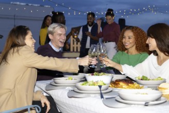 A group of friends enjoys a vibrant rooftop dinner party under string lights They share laughter