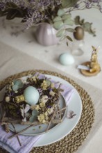 Top view of an Easter table setting featuring a plate with a rustic nest of twigs and naturally