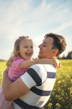 A young father and his little daughter play happily in nature in the summer. Happy parenting and