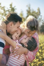 A loving family shares a heartfelt embrace surrounded by golden flowers in the countryside The