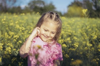 A little girl in a pink outfit smiles as she admires the flowers around her Her innocence and