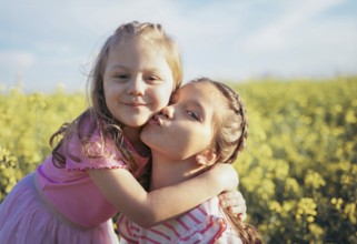 A sweet moment between two sisters as one gives the other a kiss on the cheek Their embrace