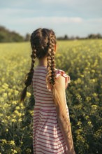 A young girl in a striped dress enjoys a moment of peace in a field of yellow flowers. Embrace