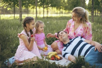 A loving family relaxes on the grass during a picnic, surrounded by nature. With fresh fruits and