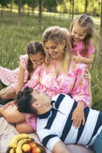 A loving family enjoys quality time together during a picnic in a peaceful green park. The parents