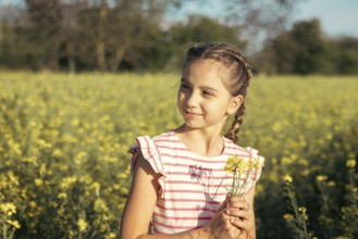 A young girl in a striped dress enjoys a moment of peace in a field of yellow flowers. Carefully