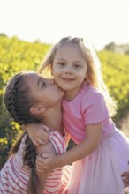 A sweet moment between two sisters as one gives the other a kiss on the cheek Their embrace