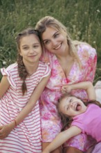 A young mother and two daughters have fun together outdoors in the summer. Family values