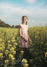 A school-age girl in a field of flowers in summer. Childhood and nature