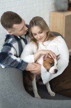 A young couple shares a tender moment with their small dog, conveying warmth and affection in a