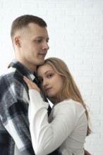 A young man and woman share a tender embrace in their home, expressing closeness and comfort. Both