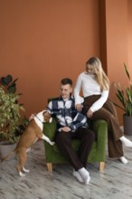 A young couple enjoys a relaxing moment with their playful Staffordshire Terrier puppy dog while