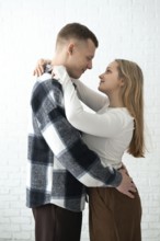 A loving couple shares a warm embrace in a brightly lit room, conveying a sense of happiness and