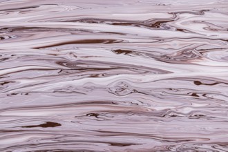 A mesmerizing marbled texture featuring swirling patterns of brown and pink acrylic paint hues. The