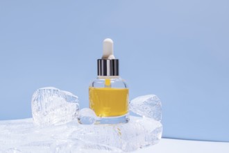A serum bottle with a dropper, filled with yellow fluid, delicately placed amongst transparent ice