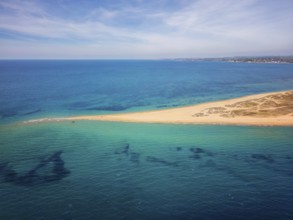 Aerial view of Epanomi Sandbar Beach on the coast of Greece. The golden sand stretches into the