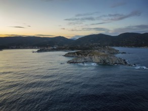A scenic view of Kalamitsi village and beach in Greece at sunset. The rugged coastline, calm sea,