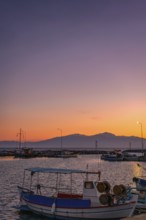 Angelochori port in Greece at sunset, featuring colorful fishing boats in the marina. Mount Olympus
