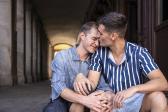 A loving gay couple shares an affectionate moment on the picturesque streets of Madrid. Their
