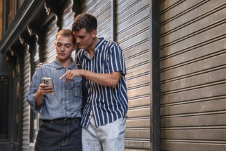 Stylish young gay couple standing together on a city street in Madrid, Spain, sharing a moment