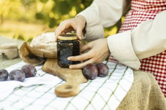 A person prepares canapes using fresh ingredients. The image includes a jar of jam, a loaf of