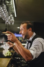 Professional bartender crafting cocktails in a chic bar. The atmosphere is lively and