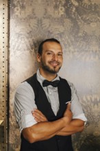 A professional bartender in a stylish cocktail bar setting, dressed in a bow tie and vest, exuding