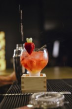 A professional bartender skillfully prepares a vibrant cocktail at a chic bar. The drink is