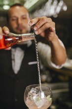 A professional bartender skillfully mixing cocktails in an elegant club with a bar spoon. The