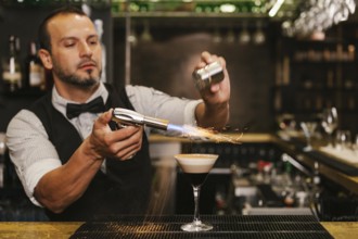 A skilled bartender carefully prepares a sophisticated cocktail at a trendy bar, showcasing expert