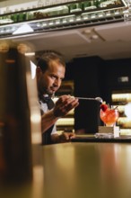 A skilled bartender creates a cocktail, focusing intently on the task. They work in a modern bar
