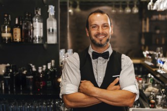 A professional bartender stands confidently in a stylish cocktail bar, surrounded by a selection of