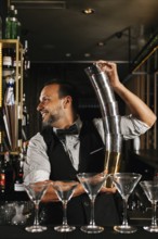 A professional bartender skillfully balances cocktail shakers, showcasing expertise and flair in a