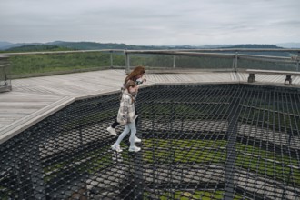 Cheerful woman and her child traversing the treetop walk at Bachledka in Slovakia