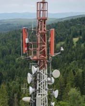 Detailed view of a telecommunication tower equipped with antennas and radio dishes, prominently