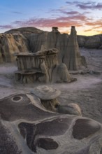 Majestic hoodoos and textured rock formations glow under a sunset sky in Bisti/De-Na-Zin