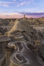 A stunning sunset illuminates the unique rock formations and hoodoos in the Bisti/De-Na-Zin