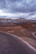 The vibrant, layered Hanksville Bentonites in Utah's desert landscape stretch under dramatic,