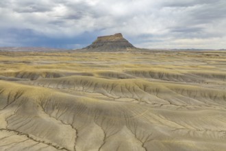 Vast desert landscape with a solitary rock formation under a dramatic sky in Hanskville, Utah. The