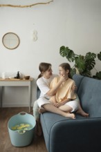 A mother and daughter enjoy a cozy self-care session at home. Sitting on a sofa, they cherish