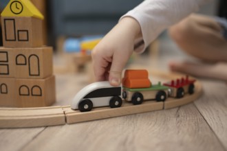 A child hand guides a wooden toy train along a curved track, surrounded by colorful building blocks